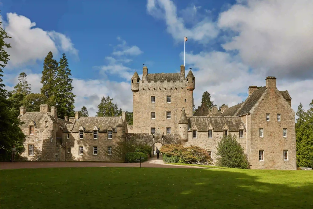 Historic castle surrounded by greenery under a blue sky, showcasing stunning architecture and charming details.