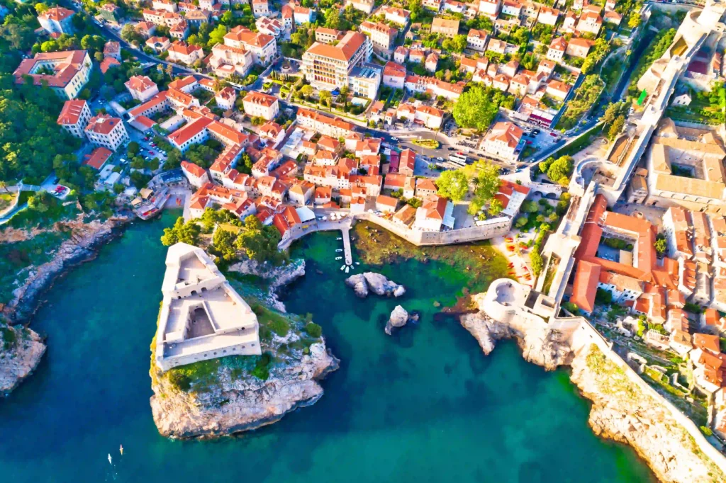 Aerial view of a coastal village with historic buildings, colorful rooftops, and crystal-clear waters. Perfect for travel inspiration.