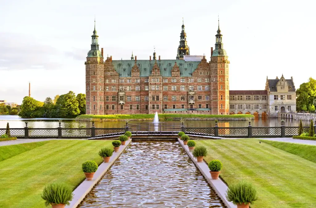Majestic castle surrounded by gardens and water, showcasing historic architecture and serene landscape.