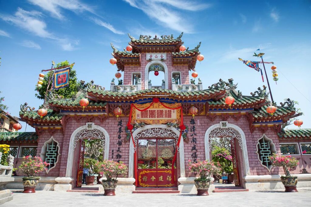 Ornate Chinese temple gate with red lanterns and intricate designs under a clear blue sky.