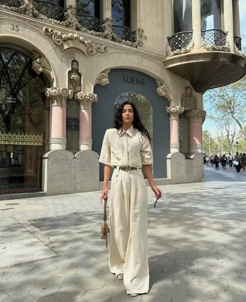 Woman in stylish beige outfit stands in front of Loewe store, showcasing urban fashion against an elegant backdrop.