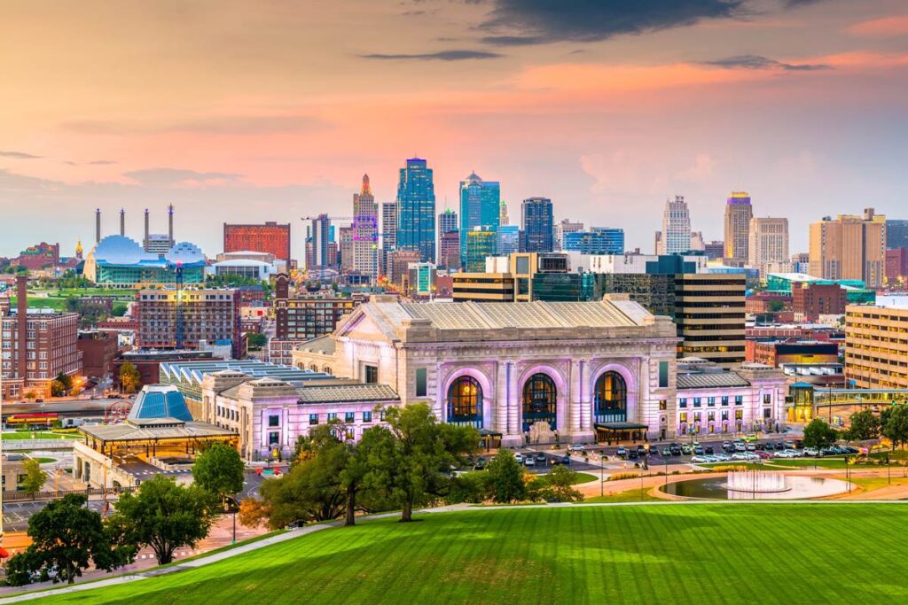 Skyline of Kansas City with historic Union Station at sunset, vibrant cityscape, modern buildings, and green park foreground.