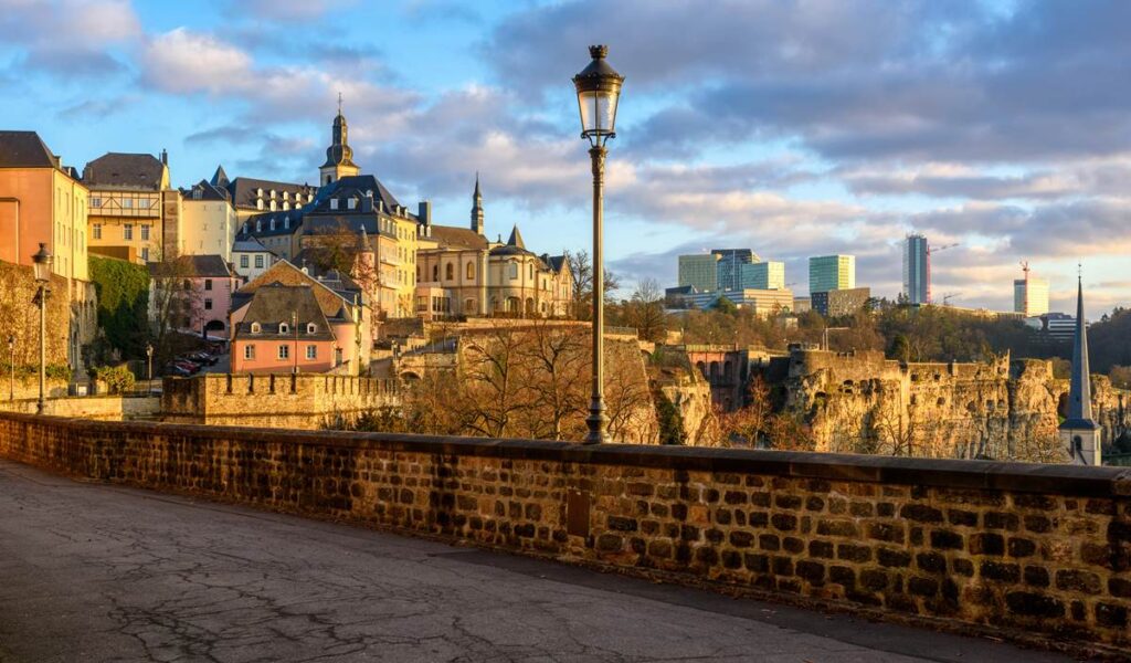 Historic Luxembourg City skyline with colorful buildings and modern skyscrapers under a blue sky.