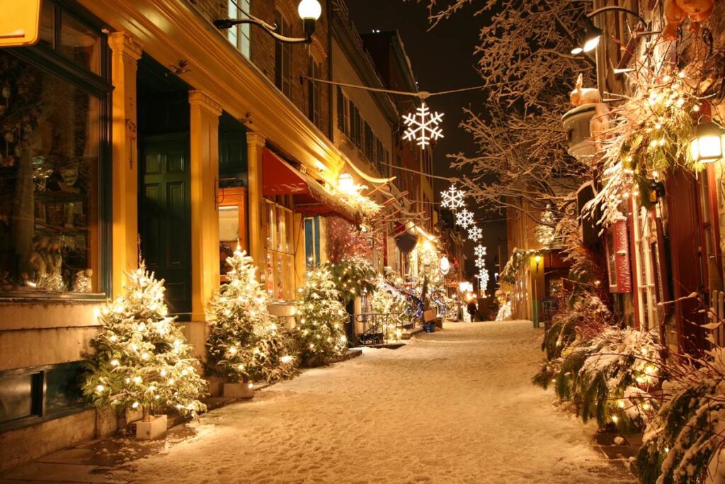 Festive street decorated with Christmas lights and snow, creating a cozy holiday atmosphere at night.