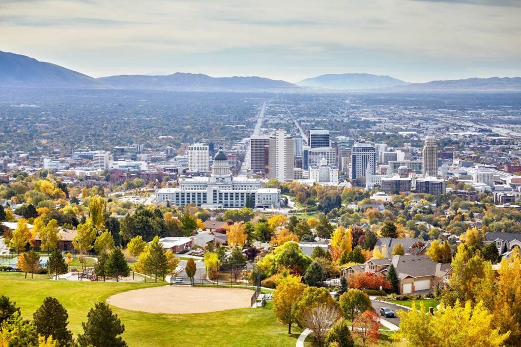 Skyline of Salt Lake City with colorful autumn trees and mountains in the background.