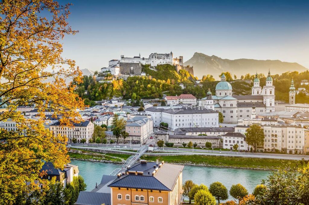 Skyline of Salzburg with Hohensalzburg Fortress in autumn, featuring historic architecture and scenic mountain backdrop.